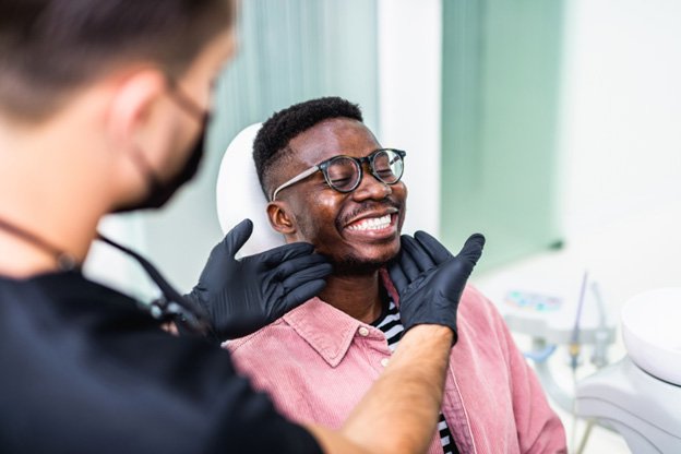 Man sitting in dental chair smiling with dentist