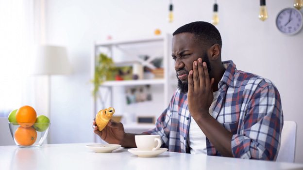 Man eating while holding his jaw in pain