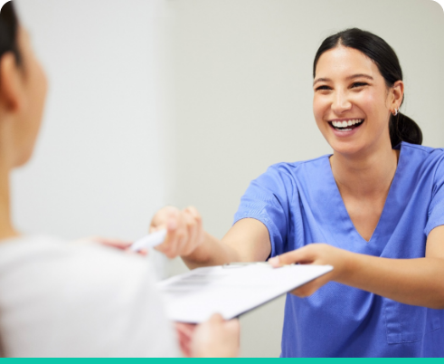 Dental assistant smiling while handing patient form