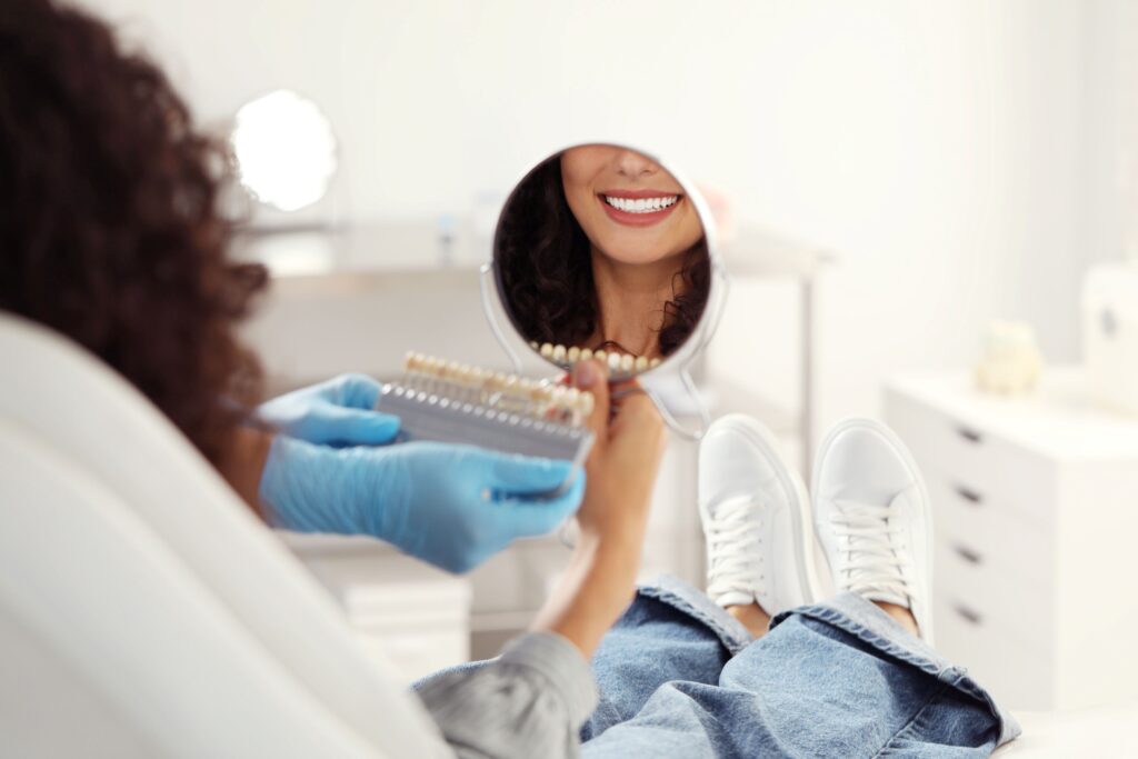 Woman's smile reflected in mirror with shade guide held to teeth